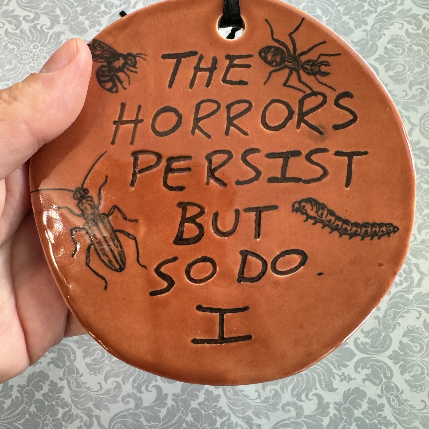 Handmade ceramic The Horrors Persist But So Do I wall hanging in red orange