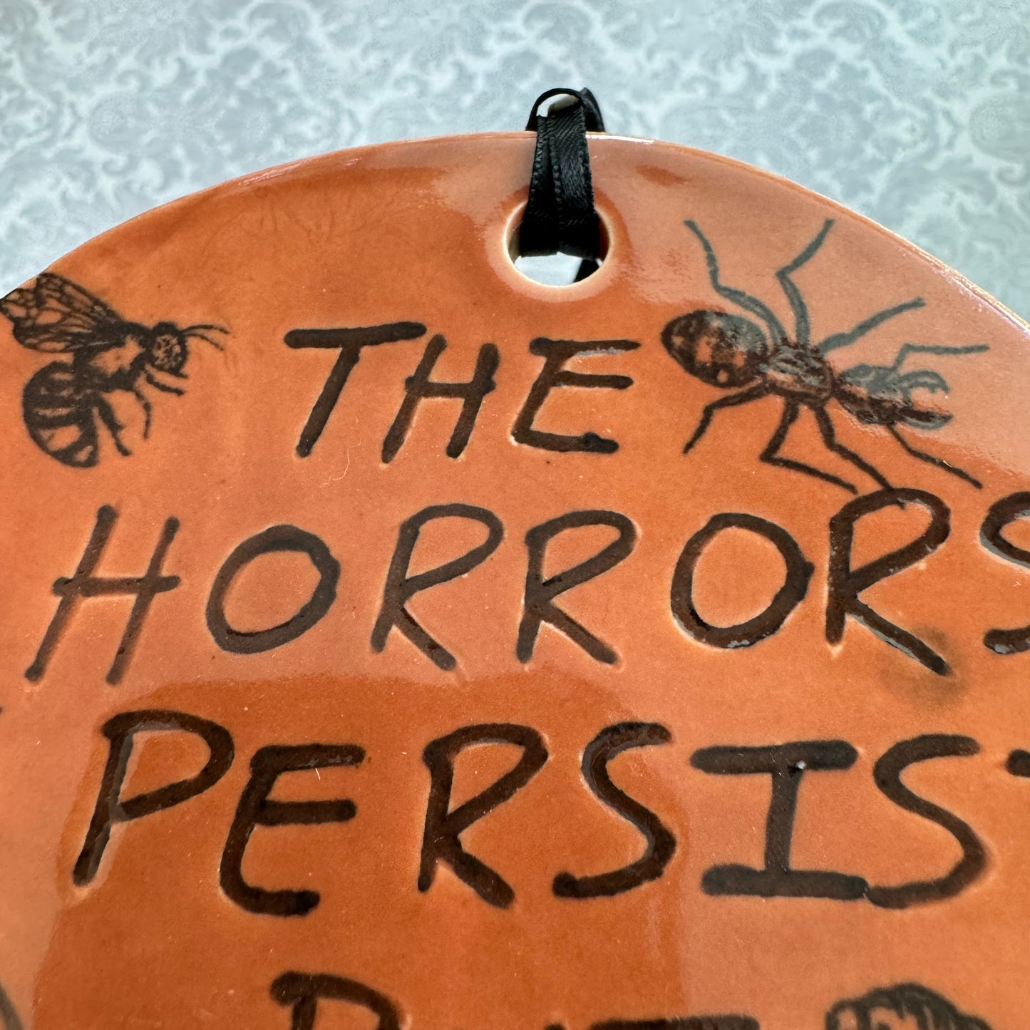 Handmade ceramic The Horrors Persist But So Do I wall hanging in red orange