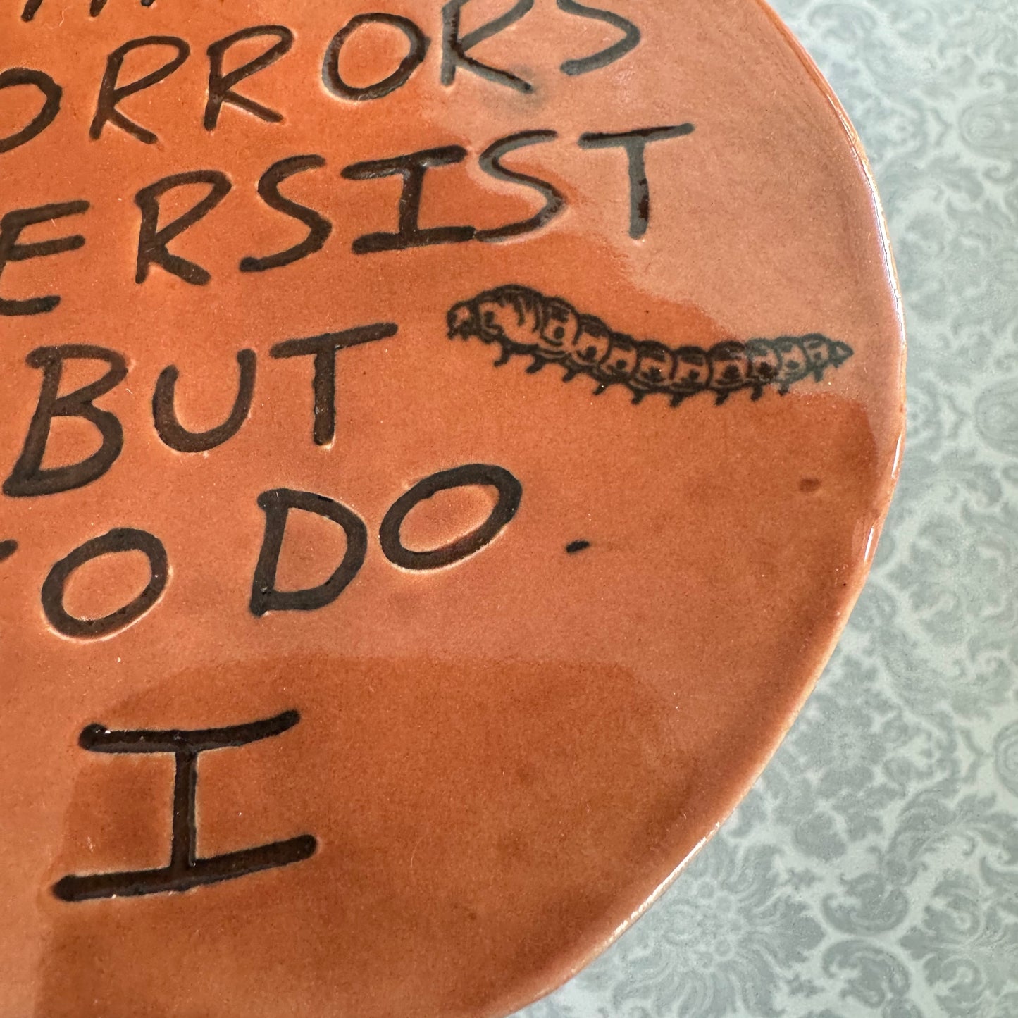 Handmade ceramic The Horrors Persist But So Do I wall hanging in red orange