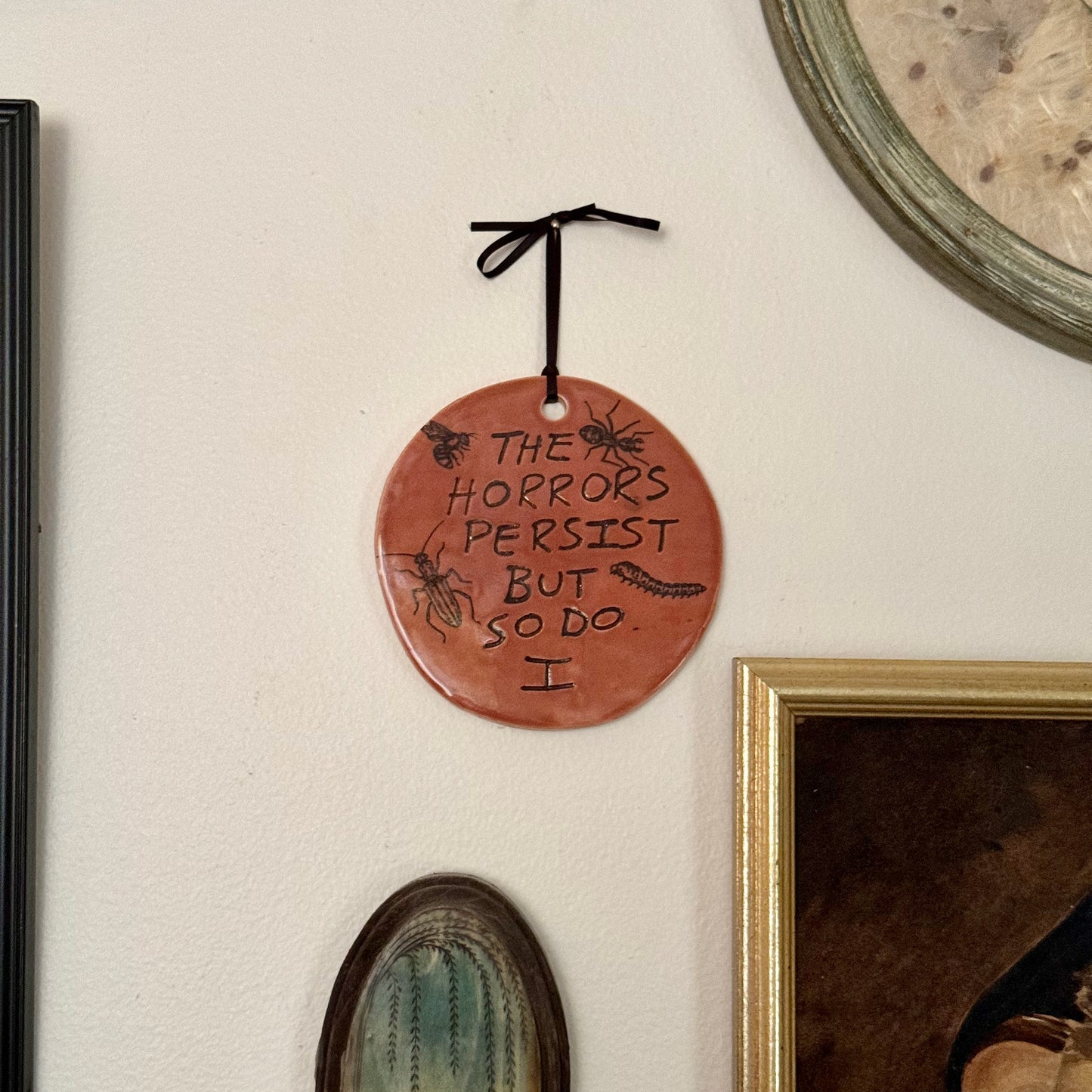 Handmade ceramic The Horrors Persist But So Do I wall hanging in red orange